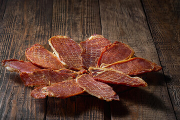 Ready-made jerky is laid out on a plate. Wooden brown background