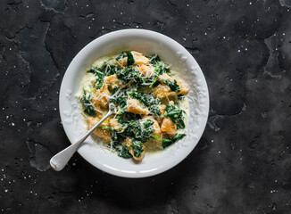 Pumpkin gnocchi with spinach cream sauce on a dark background, top view