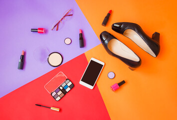 Black shoes, smartphone, glasses and cosmetics on colorful background.