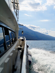 a beautiful view from the deck of a white ship by Malcesine on lake Garda with the mountains in the...