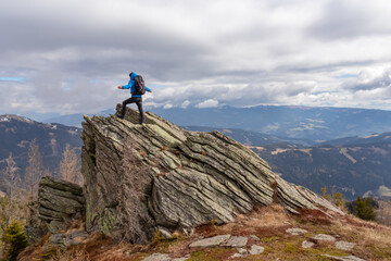 Man with a hiking backpack on a massive rock on summit Gertrusk on the way near Ladinger Spitz,...