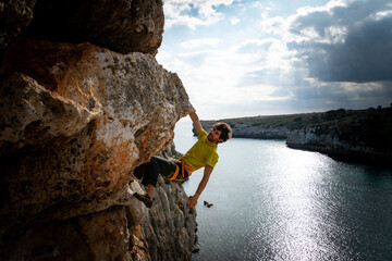 male rock climber climbs cliff 