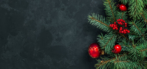 Christmas dark grunge horizontal background, top view. Fir twigs, red golden berries, baubles. Winter holidays, New Year decoration, pine tree branches, snow covered cones, flat lay, copy space.