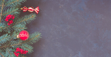 Christmas dark lilac grunge horizontal background, top view. Fir twigs, red golden berries, baubles. Winter holidays, New Year decoration, pine tree branches, snow covered cones, copy space.