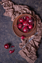 Ripe red onion bulbs in a clay bowl on a stone surface, flat lay, low key photography with free copy space for text
