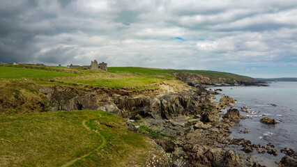 Fototapeta na wymiar Overcast cloudy sky over the rocky coast of Ireland. Beautiful nature of northern Europe. Green fields on the coast. Drone point of view.