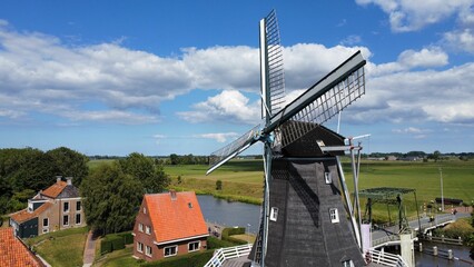 Windmill by water Canal in groningen city under blue cloudy sky - obrazy, fototapety, plakaty