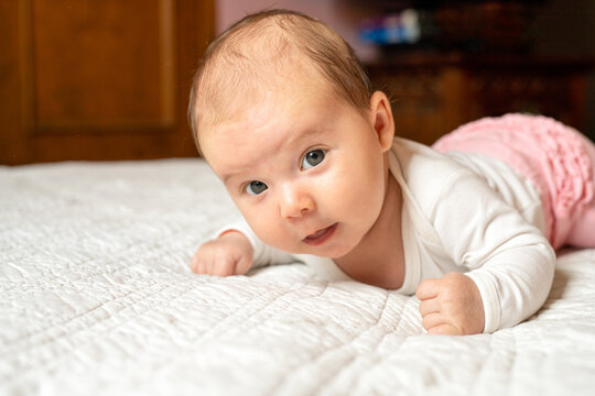 A portrait of a beautiful baby lying in the bed. Family, parenthood. Goods for newborns.