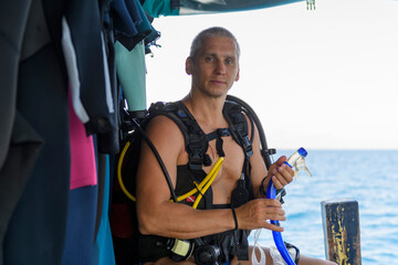 Male scuba diver preparing to dive. Wearing scuba. Caucasian man on dive boat. Underwater sports...