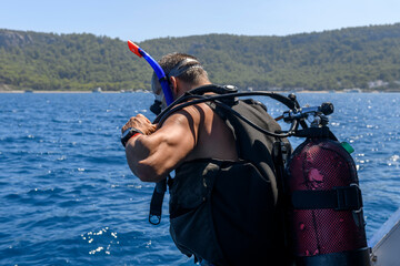 Male scuba diver preparing to dive. Wearing scuba. Caucasian man on dive boat. Underwater sports...