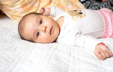 A portrait of a beautiful baby lying in the bed. Family, parenthood. Goods for newborns.
