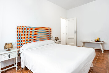 Clean bright bedroom with bed and retro print, duvet,nightstands and vintage lamps Minimalist white stylish interior