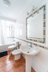 Clean bright bathroom interior with white toilet and traditional tiles. Original designed hotel space with bathtub