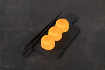 Pumpkin mousse cream cake of cylindrical shape with spiral jelly on top, on a serving board. Dark background