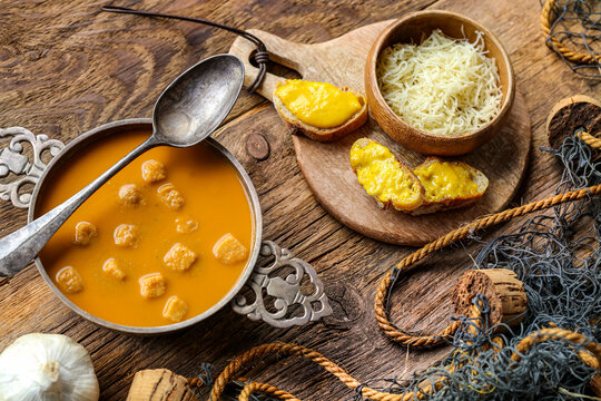 soupe de poisson avec de la sauce rouille sur table en bois