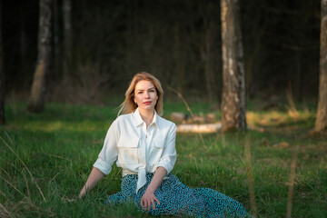 Portrait of a young beautiful fair-haired girl in the forest on the grass close-up.