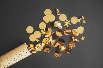 Modern golden confetti popping from festive wrapping paper on black background, new year firework...