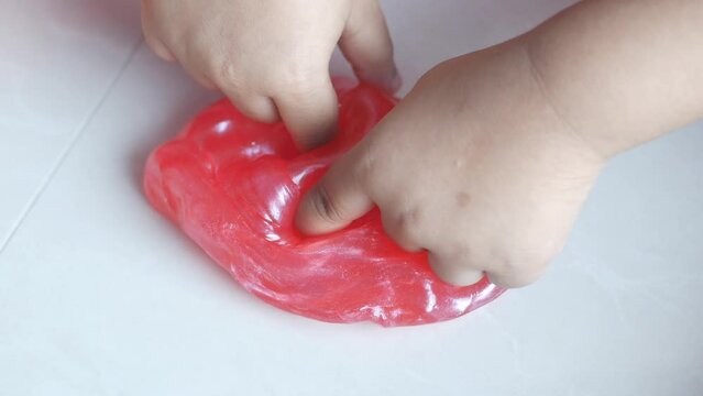 child Hand holding pink color slime 