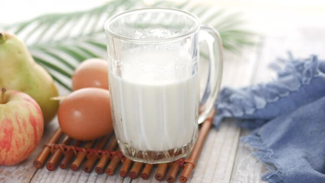 close up of glass of milk, banana and apple on table 