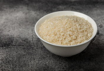 Healthy food. A bowl of steamed rice on a black marble background. Place for text, copy space. Diet porridge.