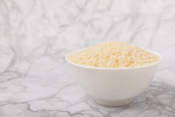 Healthy food. A bowl of steamed rice on a white marble background. Place for text, copy space. Diet porridge.