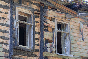 Facade of a wooden burnt house with two windows