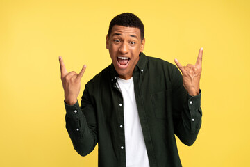 Extremely excited satisfied man showing rock and roll gesture with fingers