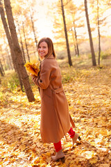 Happy young woman in a beige coast walks outdoors in autumn park, concept autumn. High quality photo