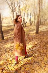 Happy young woman in a beige coast walks outdoors in autumn park, concept autumn. High quality photo