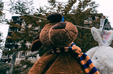 soft toys are dried after washing against the background of a burnt-out building in Mariupol