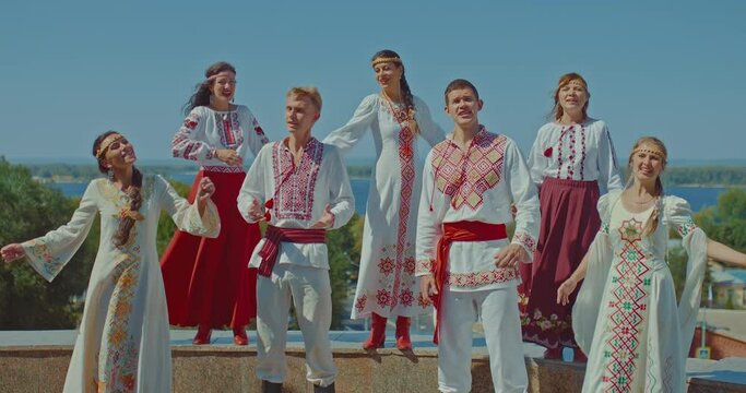 Beautiful Ukrainian women and men sing songs on the hill, they are dressed in national dresses and embroidered costumes. Ukrainian people enjoy life, songs in the park, a happy life. 4k, ProRes