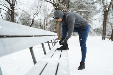 Fototapeta na wymiar Jogger man is lacing his shoes during his winter workout