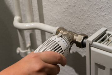 A hand turns the thermostat on a heater