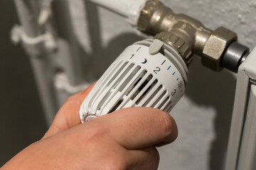 A hand turns the thermostat on a heater