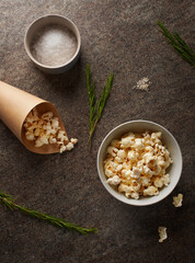Bowl and paper cone  with popcorn, salt, rosemary on marble