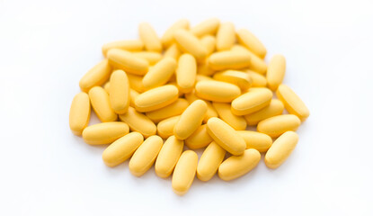 Close-up texture of yellow multivitamin tablets on white background. Healthy lifestyle concept