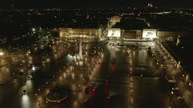 Static shot of Place de la Concorde at night. Vehicles passing illuminated square. Large advertisements on historic buildings. Paris, France