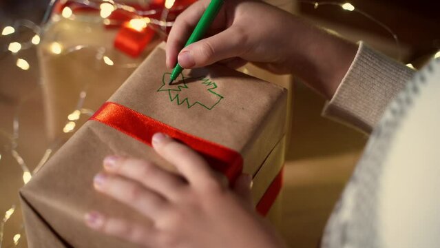 Close up child prepare gift box New year present packaging. Making hand made surprise for family. Dream. Children's paper craft school kindergarten. Christmas eve holiday lights and ringing bells.