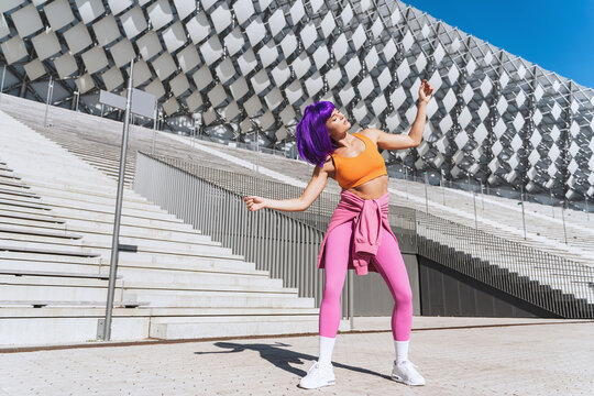 Carefree active woman dancer wearing colorful sportswear having fun on the street