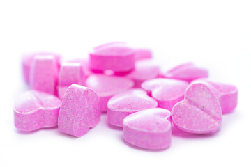 Closeup shot of pink heart shaped pills on white background.