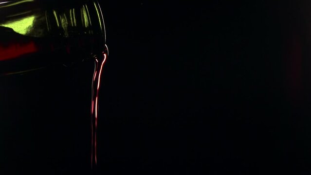 Slow motion close-up shot of red wine being poured from the bottle