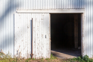 Full frame abstract texture background of a deteriorating century old barn wall and door, with newer white corrugated steel siding
