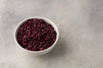 White bowl with red dry beans on a light background
