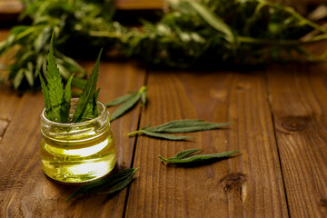 Hemp oil on bottle and fresh leaves on table