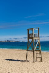 Vertical closeup of a wooden life guard tower on the sandy beach, clear sky and seascape background