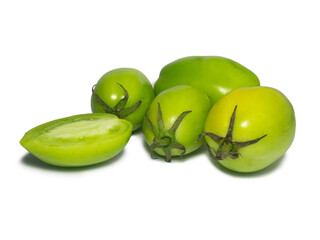 Green tomatoes on a white background. The concept of an unripe vegetable. Half cut tomato. Salting product. Healthy food.  Tomatoes lady's fingers.