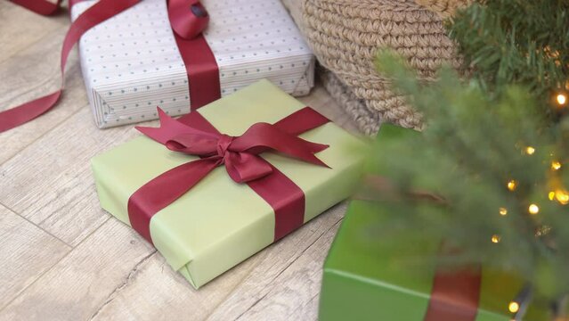 Man putting Christmas gift box under Christmas tree in living room.