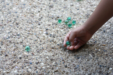 Child playing with marbles on yhe sidewalk. old-fashioned toys still in use today.
