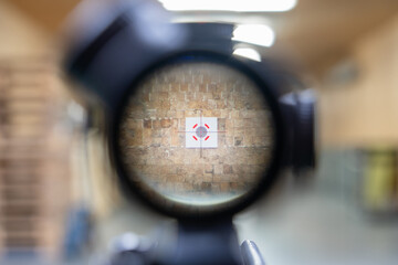 Shooting from a rifle with an optical sight in a shooting range, a view through the sight at a...