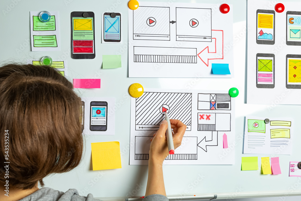 Poster website developer. a woman designer is working on sketches of mobile applications for smartphones. u